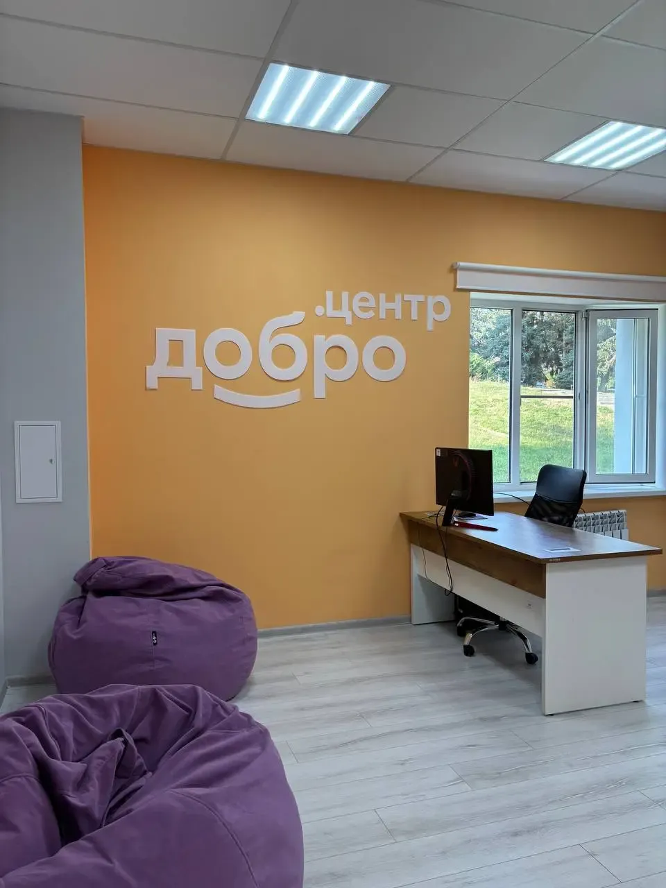 Пространство «Добро.Центр» с оранжевой стеной и фиолетовыми пуфами