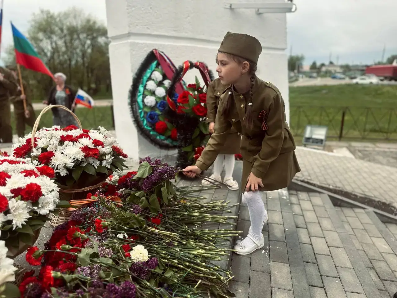 Девочка в военной форме возлагает цветы к мемориалу