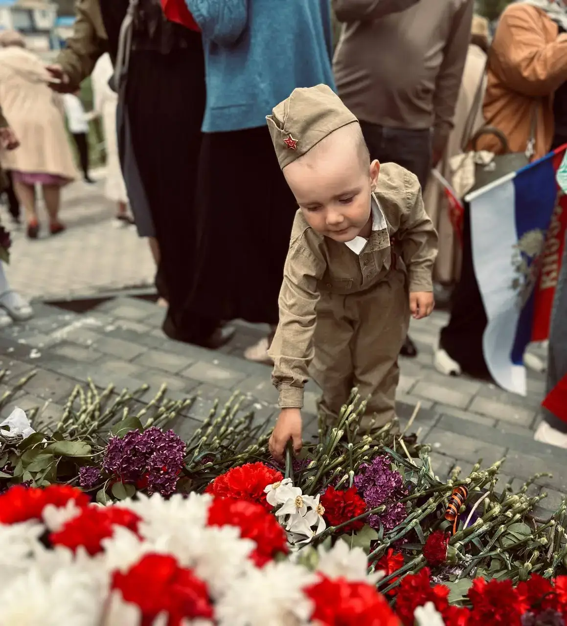 Малыш в пилотке возлагает цветы
